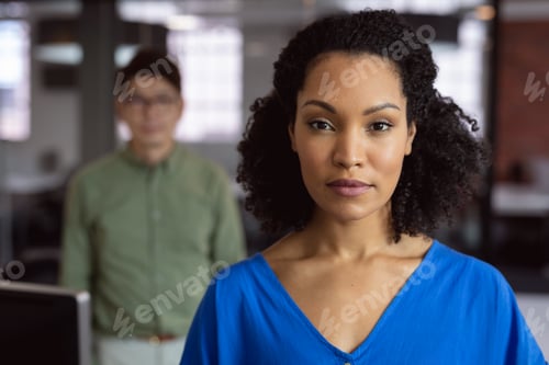Preview: Portrait of african american businesswoman standing in office with male colleague in background