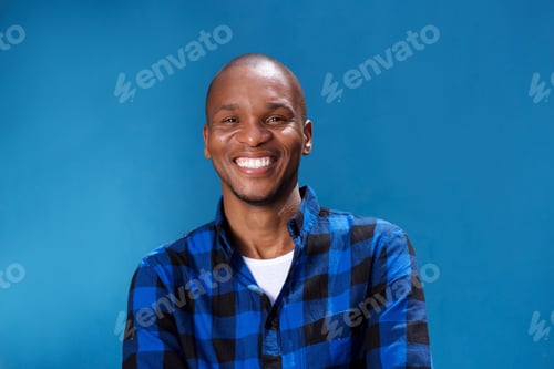 Preview: smiling young african man smiling against blue wall