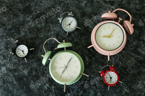 Preview: Multicolor alarm clocks on black smokey table