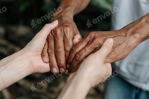 Preview: Hands of the old man and a woman hand on the wood table in sun light