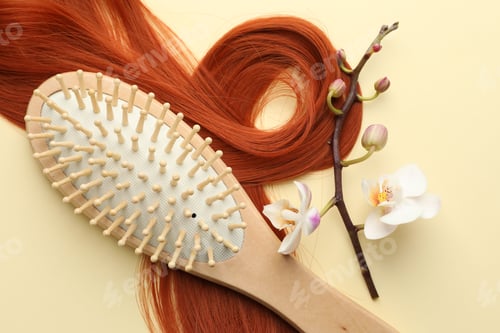 Preview: Wooden brush, orchid branch and lock of hair on beige background, flat lay