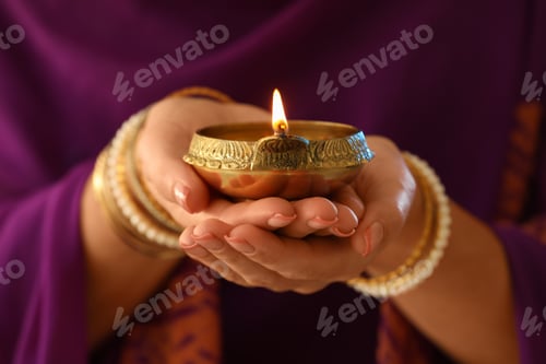 Preview: Woman holding lit diya lamp in hands, closeup. Diwali celebration