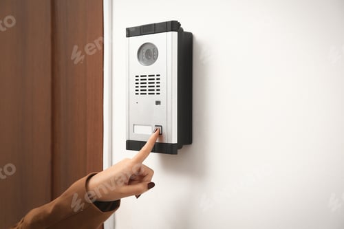 Preview: African-American woman ringing intercom with camera in entryway, closeup