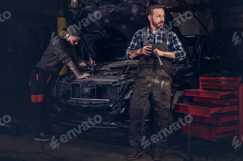 Preview: Two bearded auto mechanic working in repair garage.