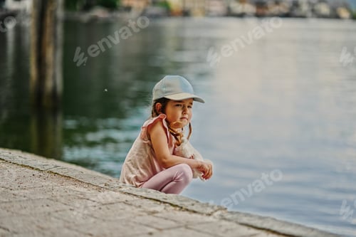 Preview: Girl in cap sit near alps lake in Hallstatt, Austria.