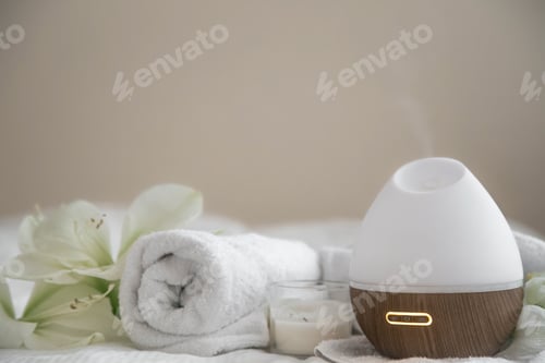 Preview: Cozy spa composition with aroma diffuser, candle and flowers.