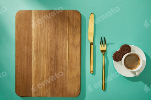 Preview: Top view of wooden cutting board with cutlery, coffee and cookies on turquoise surface