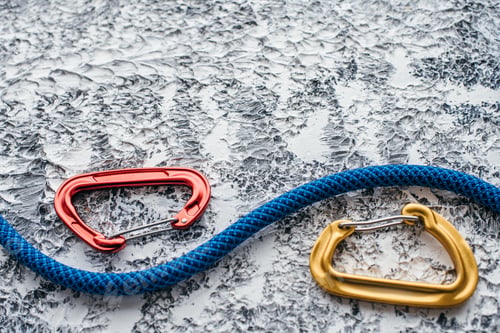Preview: Isolated photo of climbing equipment. Part of carabiner lying on the white and grey colored table