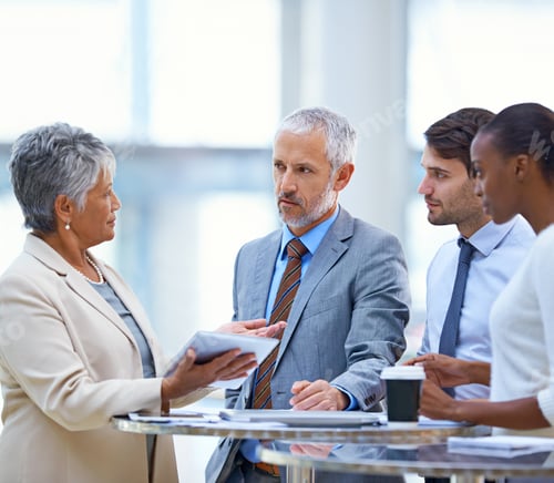 Preview: A mature businesswoman with a tablet explaining something to her colleagues in a meeting