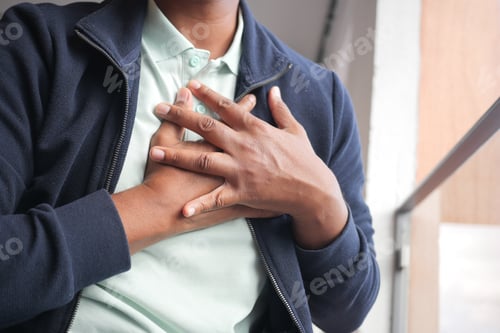 Preview: young man suffering pain in heart and holding chest with hand