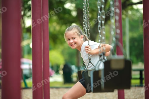 Preview: Young pretty happy smiling teenage small girl having fun on playground swings