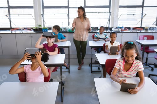 Preview: African american female teacher teaching students to use electronic devices in the class at school