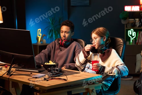 Preview: Teenage Boy and Caucasian Girl Watching Computer Screen and Eating Snack