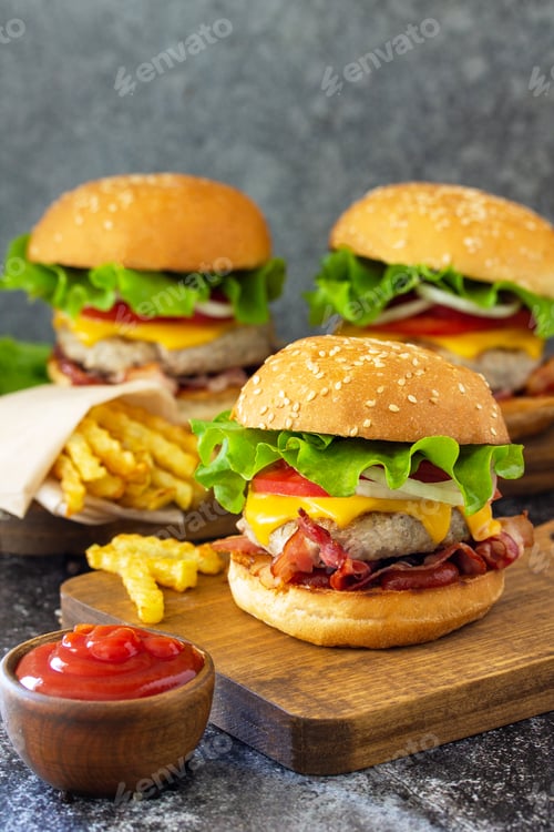 Preview: Delicious burgers with cutlet beef, bacon, french fries and ketchup on a slate table.