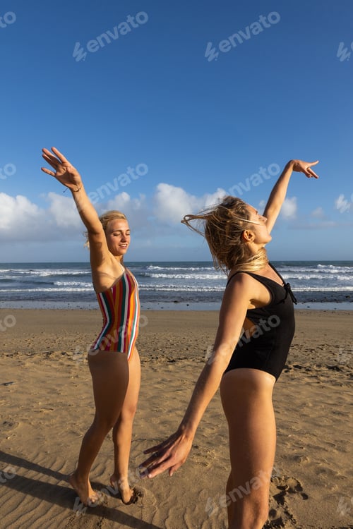 Preview: Two women having fun dancing at sunset on the beach