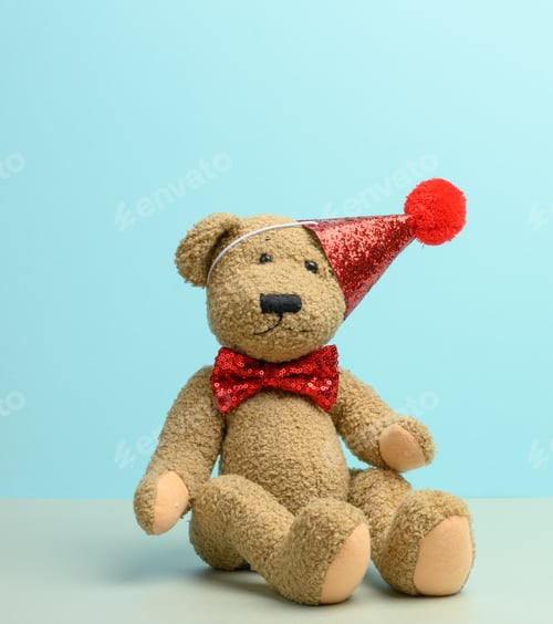 Preview: Brown teddy bear in a red cap sits on a blue background,