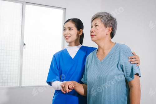 Vista previa: An Asian female nurse provides caring home care to an elderly woman, assisting with arm movement