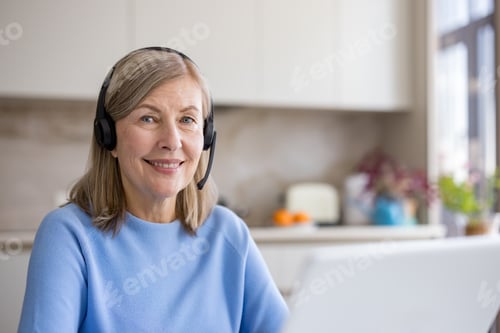 Preview: Senior woman smiling and working from home with headset