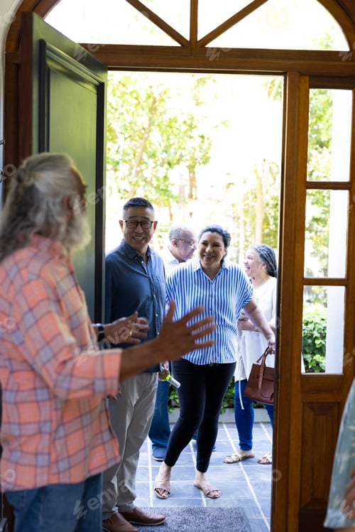 Preview: Welcoming friends, diverse senior group having cheerful conversation at home doorway