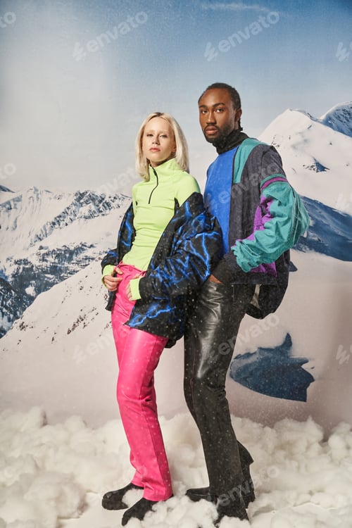 Preview: beautiful multicultural couple in trendy vibrant clothes posing on camera together, winter concept