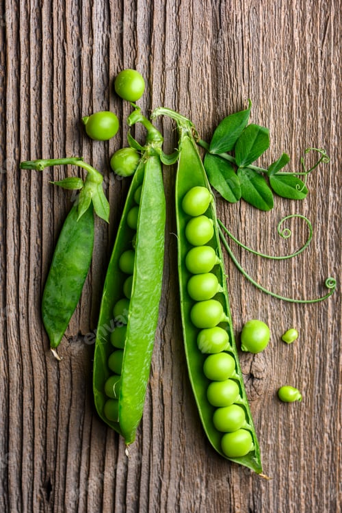Preview: Green peas arranged on wooden surface with pods