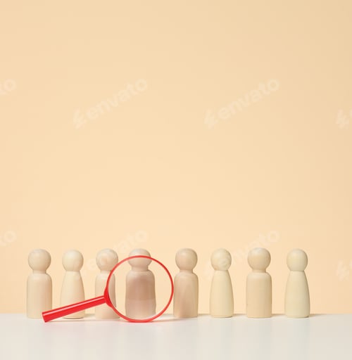 Preview: Wooden figures of men stand on a beige background and a blue plastic magnifying glass.