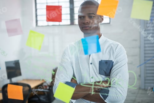 Preview: Thoughtful businessman reading sticky notes on glass