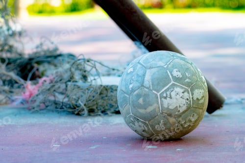 Preview: Close-up of a well-loved, heavily used football on a textured outdoor court.