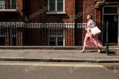 Preview: Elegant shopper walking on london sidewalk with shopping bags