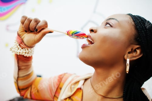 Preview: African american millennial lady at candy shop with lolipops.