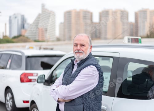 Preview: the elderly taxi driver in front of his white cab waiting for the customer