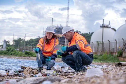 Preview: Environmental scientists or workers, wearing safety helmets and gloves, examining waste materials al