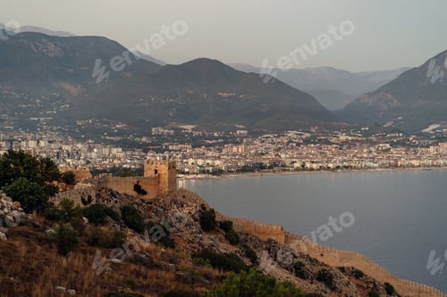 Preview: The scenic view of Red Tower, Alanya Marina and mountains on evening