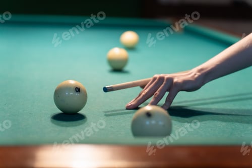 Preview: Woman playing billiards aiming white ball with cue stick. Soft focus