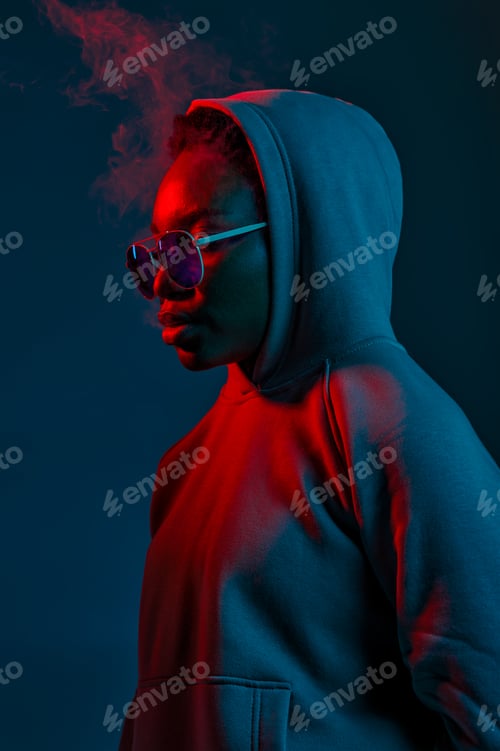 Preview: Casual hipster woman in sunglasses over dark studio wall