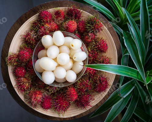 Preview: Rambutan, Malaysian sweet delicious fruits in bowl and bamboo plate in the balcony garden.