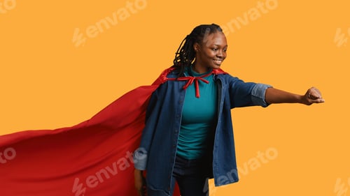 Preview: Superhero flies with cape fluttering in wind, studio background