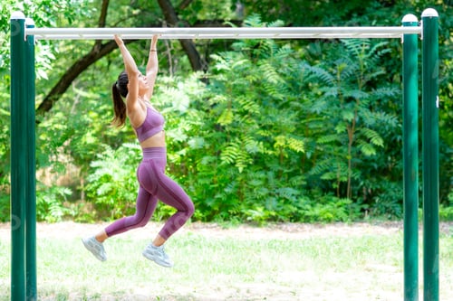 Preview: Female athlete performing monkey bar endurance drills outdoors