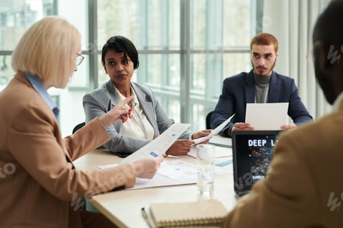 Preview: Blond female boss with financial document explaining something to subordinates
