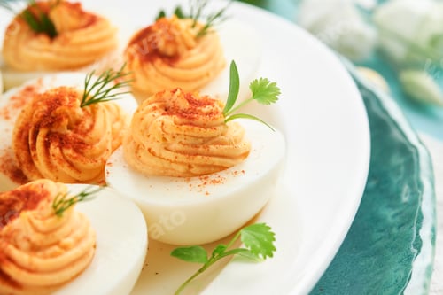 Preview: Stuffed or deviled eggs with paprika and parsley on blue plate for easter table. Traditional dish fo