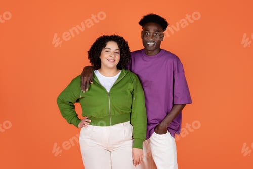 Preview: Cool young mixed race couple posing together on orange