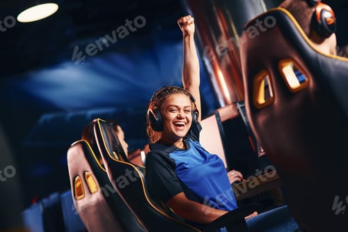 Preview: Young happy mixed race girl, female cybersport gamer raising hand up and smiling at camera while