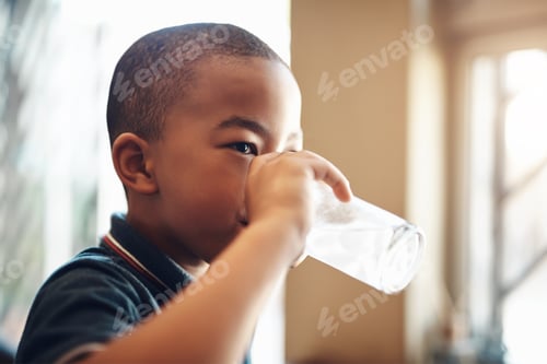 Preview: Cropped shot of a young boy drinking a glass of water at home