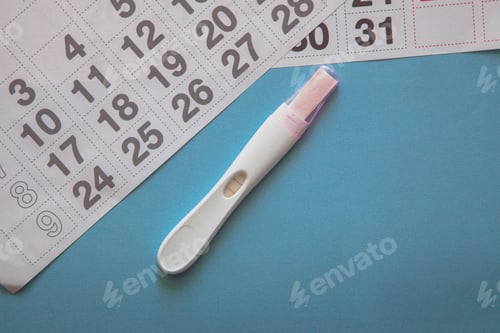 Preview: Positive pregnancy test and a calendar on the blue background. Pregnancy concept.