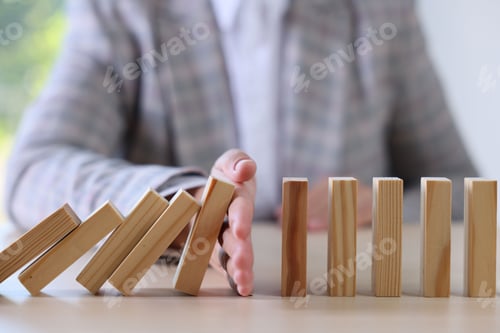 Preview: Risk. Woman stopping domino effect at table, closeup