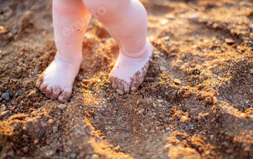 Preview: Children's bare feet in summer on a golden sandy beach close-up.
