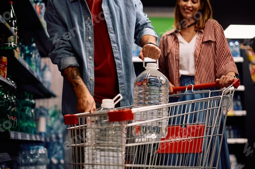 Preview: Unrecognizable couple buying purified water in a supermarket.