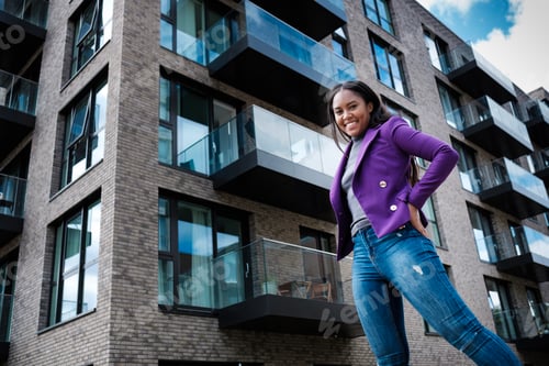 Preview: A mixed race woman model is posing with some buildings behind her.