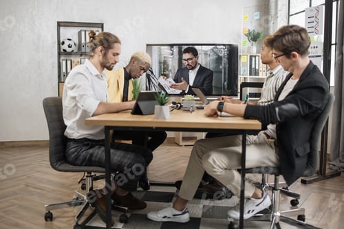 Preview: Confident young bearded caucasian man tells business program concept to his multinational colleagues