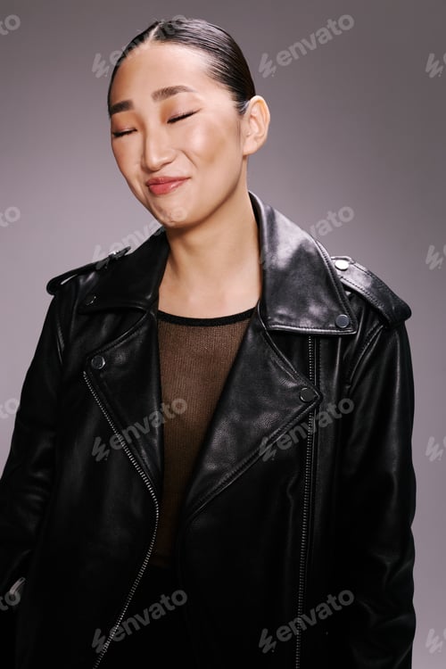 Preview: Asian woman, black leather jacket, eyes closed, smiling portrait of a stylish young woman in a